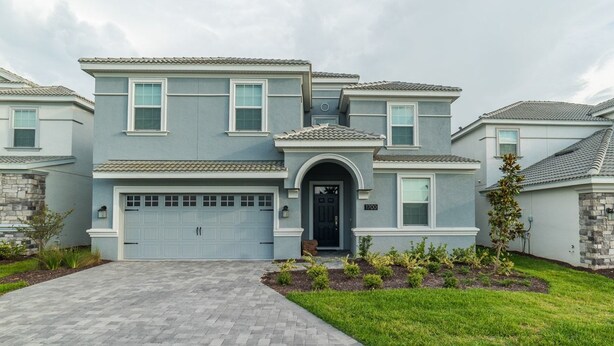 A two-story house with a garage, a front entrance with a black door, and a small porch area. - Grhmvd1700 - Champions Gate Resort - 9 Bed 5 Baths House (Davenport)