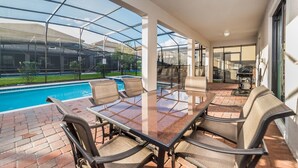 A covered outdoor area with a pool, a glass table, and chairs. - Grhshm9028 - Champions Gate Resort - 6 Bed 6 Baths House (Davenport)