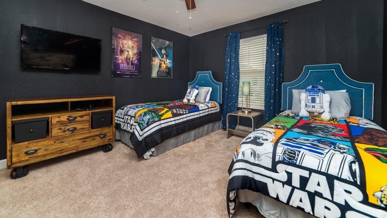Une chambre avec deux lits, une télévision et de la literie sur le thème de Star Wars.