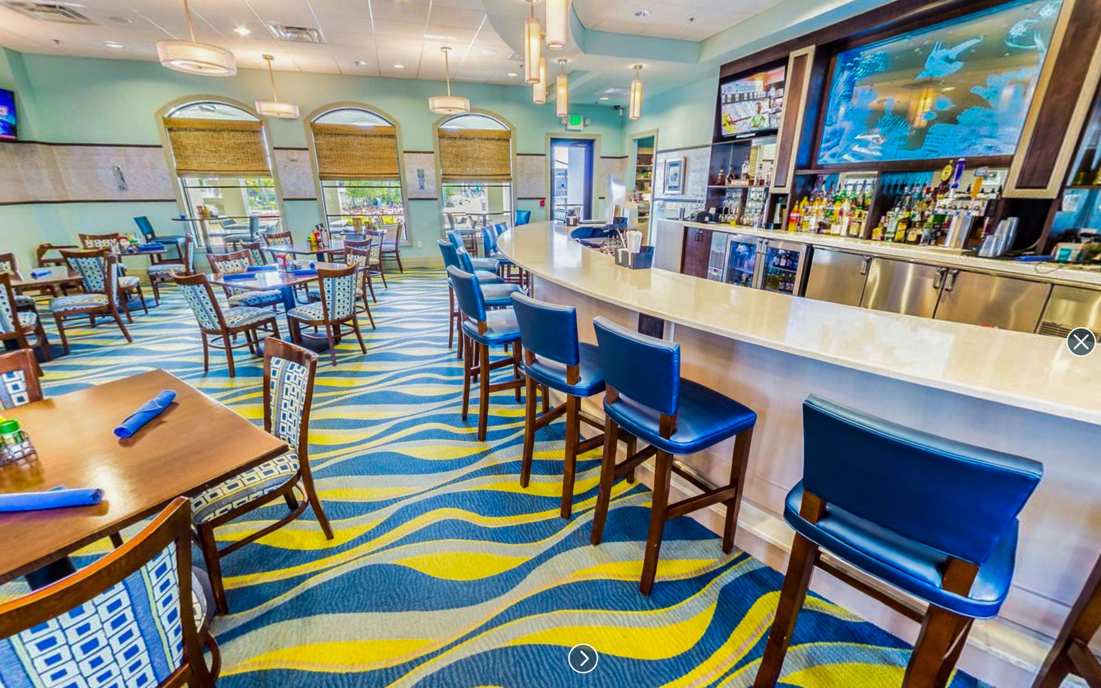 A hotel lobby with a bar area, seating arrangements, and a patterned carpet.