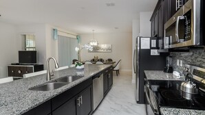 A modern kitchen with granite countertops, stainless steel appliances, and dark cabinetry.