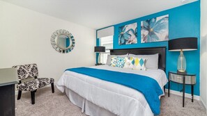 A bedroom with a bed, a chair, a nightstand, and a lamp.