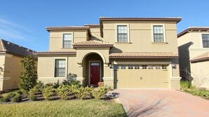 A two-story house with a red door, beige exterior, and a garage.