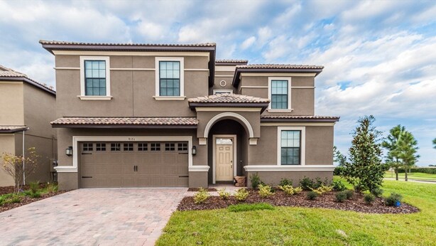 A two-story house with a garage, a front entrance with a door, and a landscaped front yard. - Grhcdw9151 - Champions Gate Resort - 9 Bed 5 Baths House (Davenport)