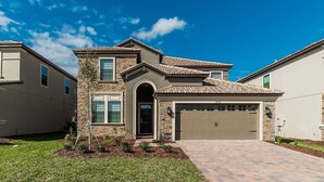 A two-story house with a stone facade, a tiled roof, and a garage. - Grhcdw9157 - Champions Gate Resort - 6 Bed 6 Baths House (Davenport)
