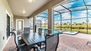 A covered patio with a pool, outdoor seating, and a view of the surrounding landscape. - Grhcdw9157 - Champions Gate Resort - 6 Bed 6 Baths House (Davenport)