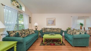 A living room with two green sofas, a green coffee table, and a patterned rug.