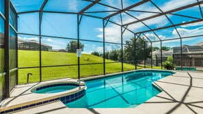 A swimming pool with a hot tub, surrounded by a glass enclosure, and a grassy area in the background. - Grhlk2740 - Emerald Island Resort - 7 Bed 4 Baths House (Kissimmee)