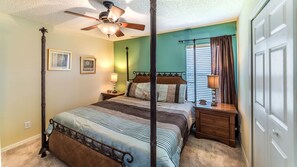 A four-poster bed with a ceiling fan, a nightstand with a lamp, and a window with curtains. - Grhlk2740 - Emerald Island Resort - 7 Bed 4 Baths House (Kissimmee)