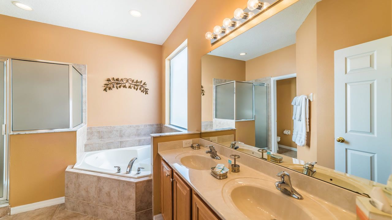 A bathroom with a double sink, a bathtub, and a large mirror.