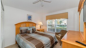 A bedroom with a bed, a nightstand, a chair, a window with blinds, and a ceiling fan. - Grhokc8484 - Emerald Island Resort - 5 Bed 4 Baths House (Kissimmee)