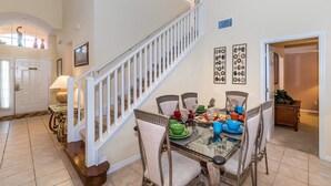 A dining area with a glass table, wicker chairs, and a staircase with white railings. - Grhokc8484 - Emerald Island Resort - 5 Bed 4 Baths House (Kissimmee)