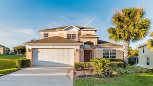 A two-story house with a garage, a front door, and a large tree in the front yard. - Grhokc8484 - Emerald Island Resort - 5 Bed 4 Baths House (Kissimmee)