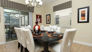 A dining area with a dark wooden table, white chairs, and a large vase centerpiece.