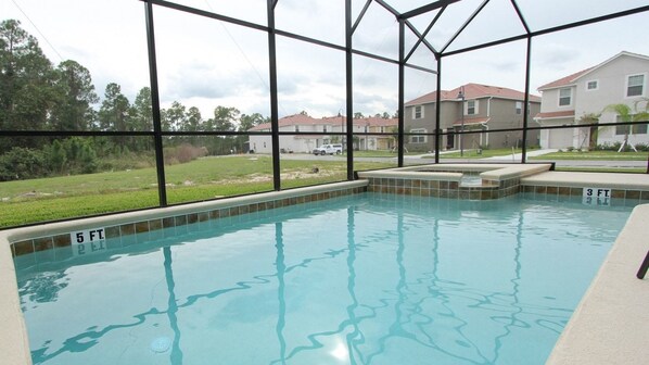 A swimming pool with clear water, surrounded by a glass enclosure, and a sign indicating a depth of 5 feet.