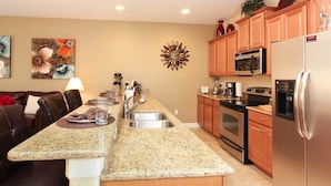A modern kitchen with granite countertops, stainless steel appliances, and wooden cabinets. - Grhbch3043 - Paradise Palms Resort - 4 Bed 3 Baths Townhouse (Kissimmee)