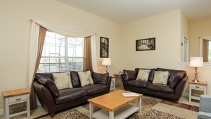 A living room with two brown leather sofas, a wooden coffee table, and a patterned rug. - Grhbch3057 - Paradise Palms Resort - 5 Bed 4 Baths Townhouse (Kissimmee)