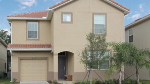 A two-story house with a beige exterior, a red-tiled roof, and a garage door. - Grhcap8858 - Paradise Palms Resort - 6 Bed 5 Baths House (Kissimmee)