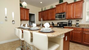 A kitchen with wooden cabinets, a granite countertop, a stainless steel microwave, and a coffee maker. - Grhsug8925 - Paradise Palms Resort - 5 Bed 5 Baths House (Kissimmee)