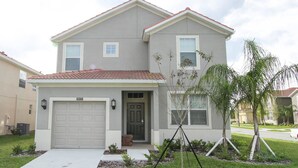 A two-story house with a garage, a front door, and a small porch. - Grhsug8925 - Paradise Palms Resort - 5 Bed 5 Baths House (Kissimmee)