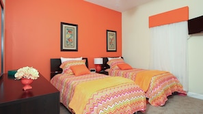 Een hotelkamer met twee bedden, oranje wanden en een televisie.