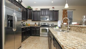 Eine moderne Küche mit dunklen Schränken, Edelstahlgeräten, Granit Arbeitsplatten und einem eingebauten Backofen.
