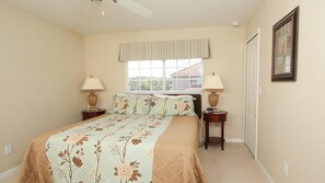 A bedroom with a bed, two bedside tables, a window with a striped valance, and a framed picture on the wall. - Grhcpr8950 - Paradise Palms Resort - 5 Bed 4 Baths Townhouse (Kissimmee)