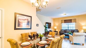 A dining area with a table set for four, a sofa, and a TV in the background.
