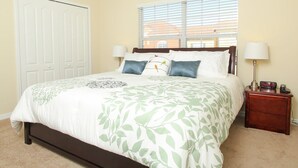 A neatly made bed with a leaf-patterned bedspread, two bedside lamps, and a nightstand with a clock and a radio. - Grhmap8952 - Paradise Palms Resort - 4 Bed 3 Baths Townhouse (Kissimmee)