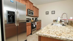 A kitchen with stainless steel appliances, wooden cabinets, granite countertops, and a built-in microwave. - Grhmap8952 - Paradise Palms Resort - 4 Bed 3 Baths Townhouse (Kissimmee)