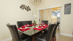 A dining area with a glass table, red napkins, and black chairs.