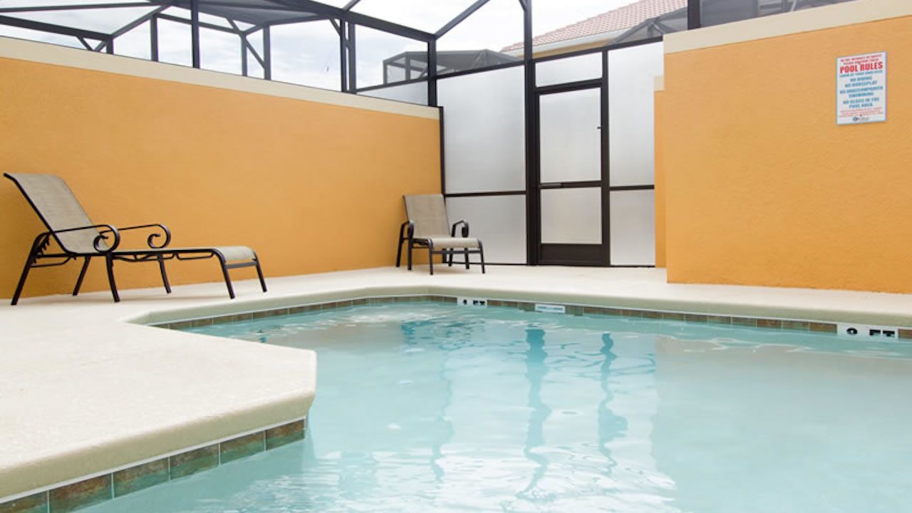 Una piscina interior con dos sillones de descanso y techo de cristal.