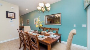 A dining room with a wooden table set for four, a vase with flowers, and a chandelier. - Grhcup8968 - Paradise Palms Resort - 4 Bed 3 Baths Townhouse (Kissimmee)