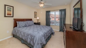 A bedroom with a bed, a nightstand, a TV, a ceiling fan, and a window with curtains. - Grhcpr8971 - Paradise Palms Resort - 4 Bed 3 Baths Townhouse (Kissimmee)