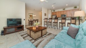 A living room with a TV, sofa, coffee table, and dining area. - Grhcpr8971 - Paradise Palms Resort - 4 Bed 3 Baths Townhouse (Kissimmee)