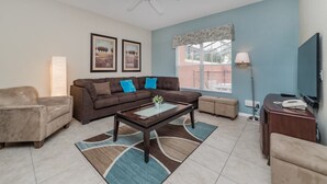 A living room with a brown sofa, beige armchair, and a coffee table with a vase. - Grhmap8975 - Paradise Palms Resort - 4 Bed 3 Baths Townhouse (Kissimmee)