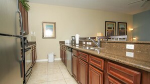 A kitchen with granite countertops, stainless steel appliances, wooden cabinets, and a tiled floor. - Grhmap8975 - Paradise Palms Resort - 4 Bed 3 Baths Townhouse (Kissimmee)