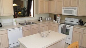 A kitchen with beige cabinets, a white microwave, a stove, a dishwasher, and a sink. - Grhlic2691 - Emerald Island Resort - 7 Bed 5 Baths House (Kissimmee)
