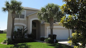 A two-story house with a garage, palm trees, and a well-maintained lawn. - Grhlic2691 - Emerald Island Resort - 7 Bed 5 Baths House (Kissimmee)