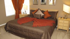 A bedroom with a large bed, two bedside tables, a nightstand, and a mirror on the wall. - Grhlic2691 - Emerald Island Resort - 7 Bed 5 Baths House (Kissimmee)