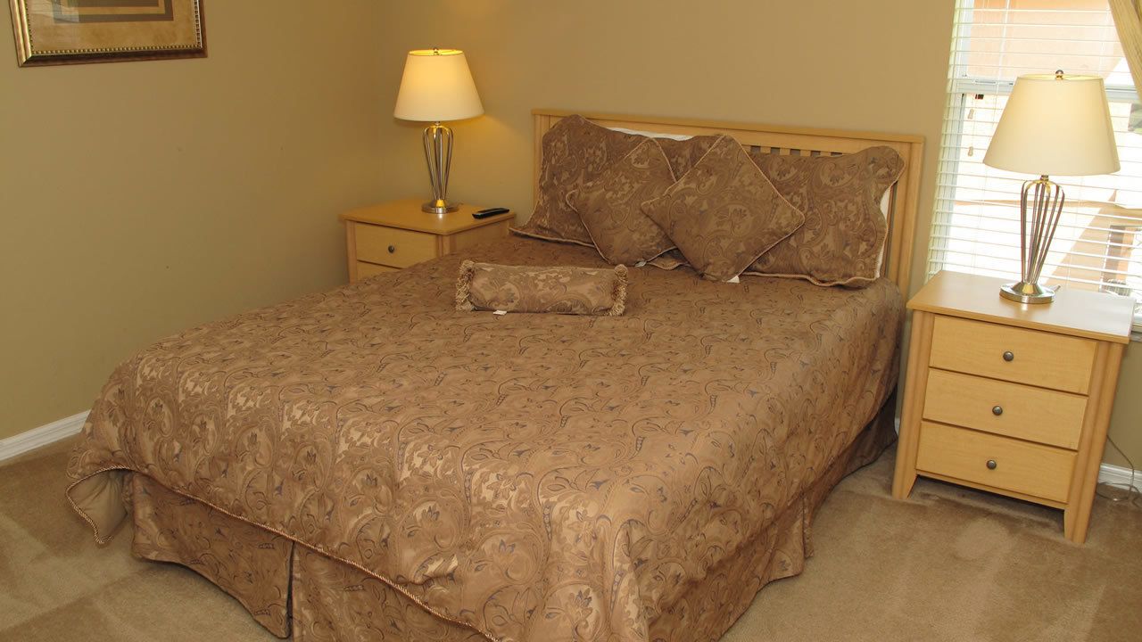 A bedroom with a large bed, two bedside tables, and a window with blinds.