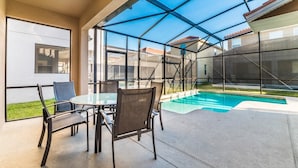 Eine überdachte Terrasse mit Pool, Sitzgelegenheit im Freien und großen Fenstern.