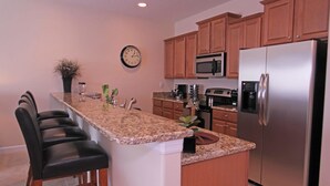 A modern kitchen with granite countertops, stainless steel appliances, and wooden cabinets. - Grhcal8974 - Paradise Palms Resort - 4 Bed 3 Baths Townhouse (Kissimmee)