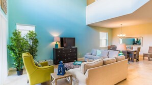 Una sala de estar con sofá, sillón, televisor y un comedor con sillas y mesa.