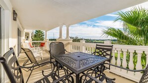 A balcony with a table and chairs, a white railing, and a view of palm trees and greenery. - Grhccr1368-302 - Reunion Resort - 3 Bed 3 Baths Townhouse (Kissimmee)