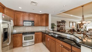 A modern kitchen with wooden cabinets, stainless steel appliances, and a granite countertop. - Grhccr1368-302 - Reunion Resort - 3 Bed 3 Baths Townhouse (Kissimmee)