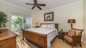 A bedroom with a bed, a chair, a lamp, a ceiling fan, and a window with a view of greenery. - Grhccr1368-302 - Reunion Resort - 3 Bed 3 Baths Townhouse (Kissimmee)
