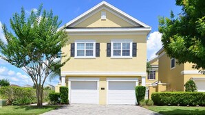 A two-story house with a yellow facade, white trim, and a central garage.