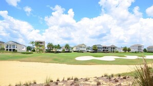 A golf course with sand bunkers and houses in the background.
