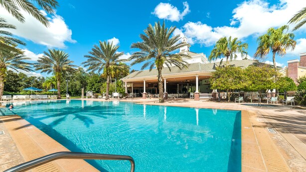 A swimming pool with palm trees, a covered area, and a building with a dome roof.